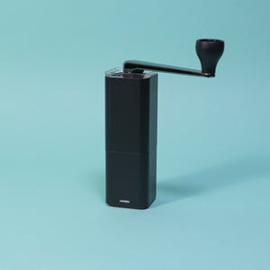 Black metal monolithic grinder with clear lid and black chromed handle.