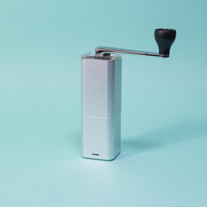 Silver monolithic grinder with clear lid and chrome handle.