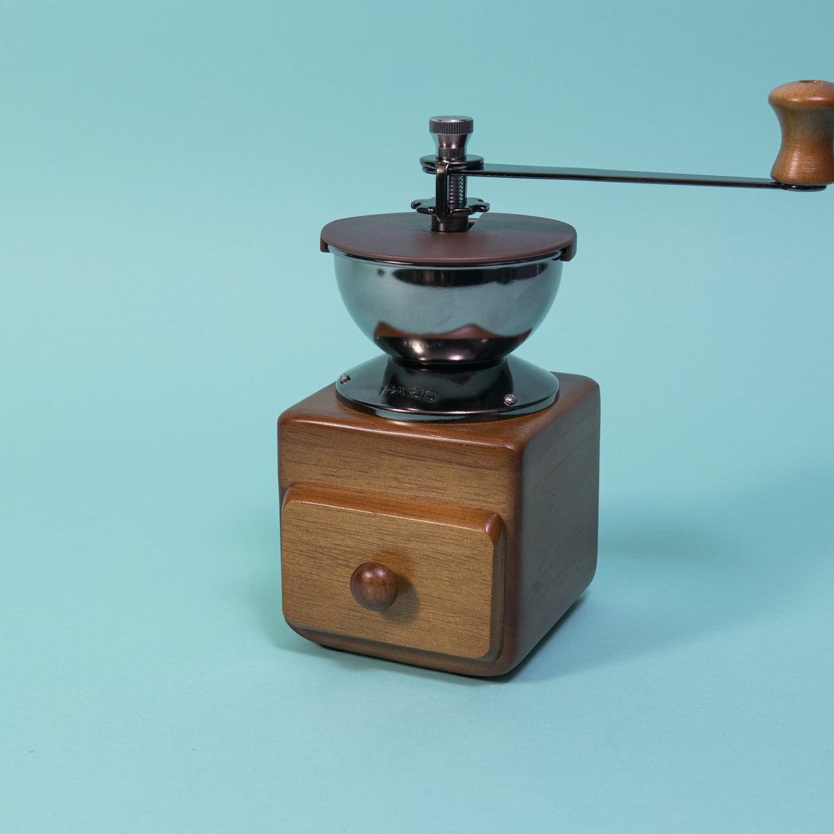 Wooden cube and drawer with dark metal grinder hopper and handle on top