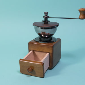 Wooden cube and drawer with dark metal grinder hopper and handle on top