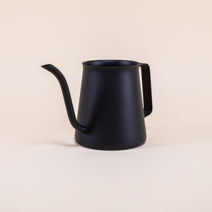 All black metal kettle with flared top, gooseneck spout, and handle on a light background.
