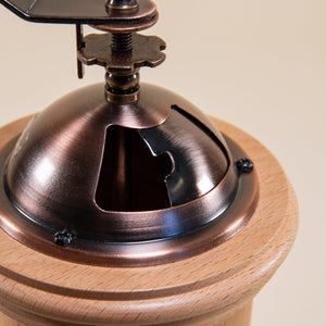 Close up of open sliding metal hopper gate on a cylindrical wood grinder with bronze metal grinder hopper, with sliding metal gate, and handle with wood knob