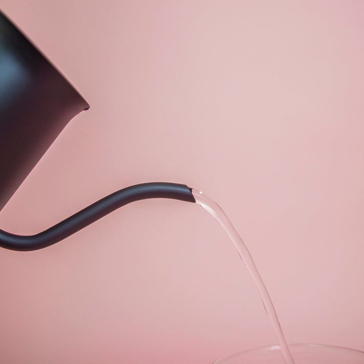 All black metal kettle with flared top, gooseneck, and handle pouring water.