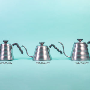 Three silver beehive-shaped stainless steel kettles of varying sizes with wave-shaped black plastic handles and round black plastic lid knobs with flat tops set against a light blue background.