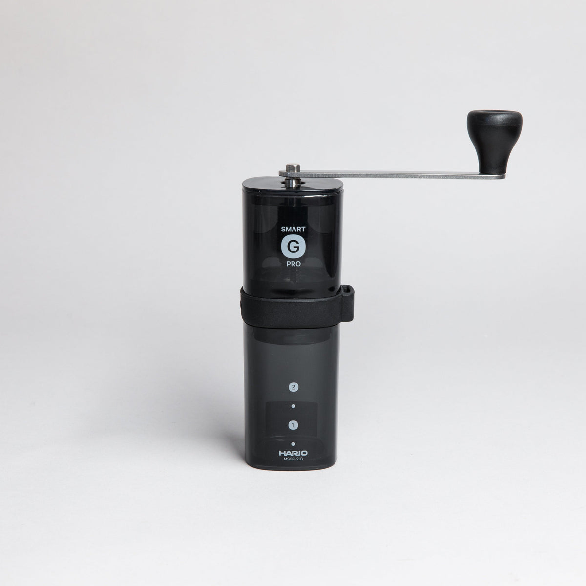Black transparent plastic coffee mill with a slim metal handle attached to the shaft of the grinder.