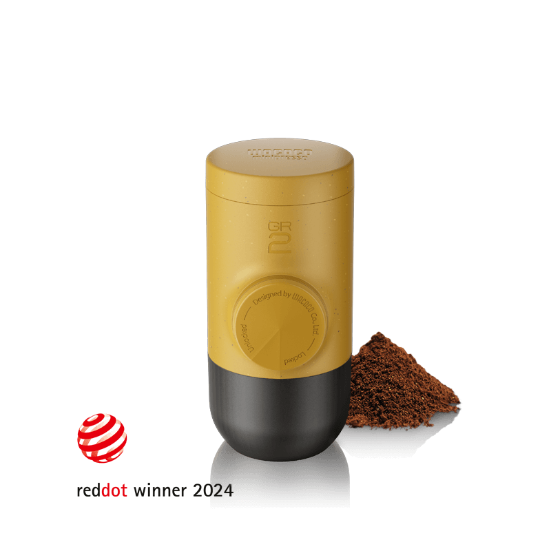 Wacaco Minipresso GR2 portable espresso maker in Amber Yellow with ground coffee, Red Dot Design Award winner 2024